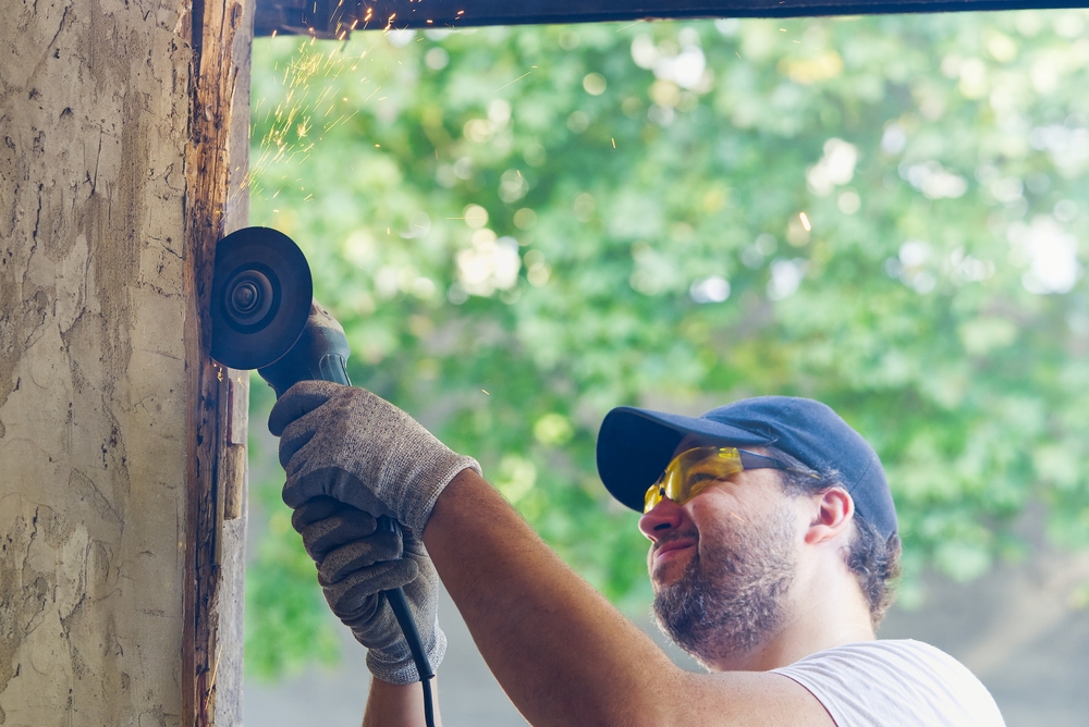 Technician performing emergency garage door repair on a damaged residential garage door