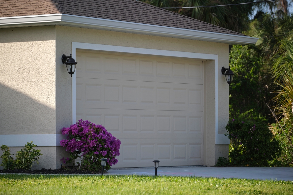 Technician winterizing a residential garage door with weather seals and insulation for harsh winter conditions